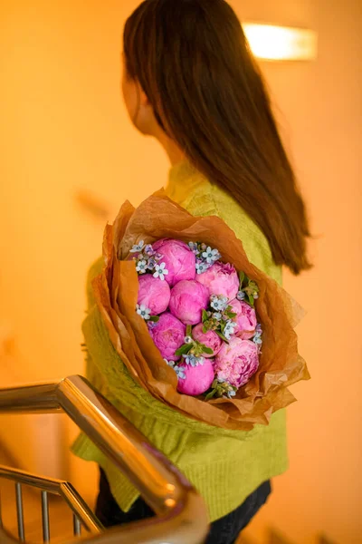 สาวสวยผมด งในสเวตเตอร โพสก อดอกไม หราของดอกโบต ชมพ สดสดในภายในบ นได — ภาพถ่ายสต็อก