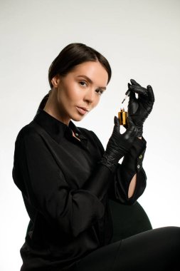 Çekici esmer manikür ustasının portresi ellerinde altın tırnak cilası şişesi, beyaz arka plan. Güzellik salonu için içerik