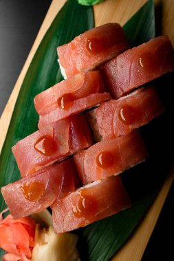 Philadelphia ton balıklı suşi rulosu. Tahta tahtada muz yapraklarıyla servis edilen teriyaki soslu. Üst Manzara. Suşi menüsü.