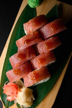 Philadelphia ton balıklı suşi rulosu. Tahta tahtada muz yaprağı ve zencefille servis edilen teriyaki sosuyla birlikte. Üst Manzara. Sushi yenge menüsü.