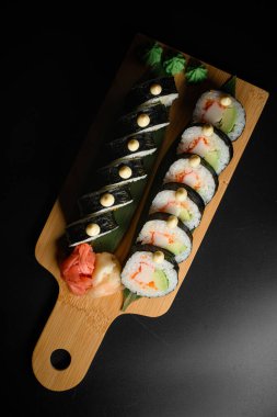 Lezzetli suşi rulo futomaki 'nin dikey görüntüsü avokado ve ahşap servis tahtasının üzerinde yengeç eti. Mesaj için yer var. Asya gıda kavramı