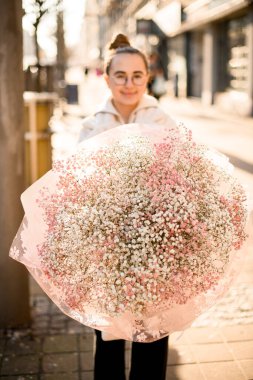 Çiçekçi kız ellerinde kocaman renkli bir buket çigila çiçeğinin seçici odağı. Ön manzara. Bulanık arkaplan