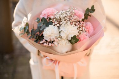 Çiçek açan taze karanfil buketi pembe ve beyaz renkli çiçekler ve kadınların elinde yeşil okaliptüs dalları. Güzel bir gelin buketi. Yatay görünüm