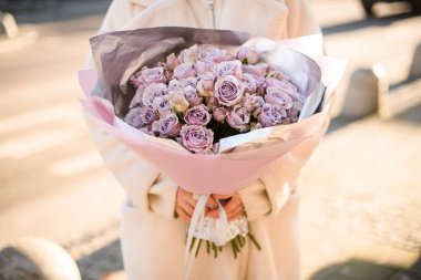 Açık havada kızların elindeki narin buketlere ya da menekşe güllerine odaklan. Tatil için canlı bir demet menekşe çiçeği.