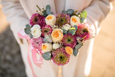 Bir buket taze ranunculus, güller ve okaliptüs pembe kalp şeklinde bir kutunun içinde çiçekçi kadının ellerinde. Üst Manzara. Bulanık arkaplan