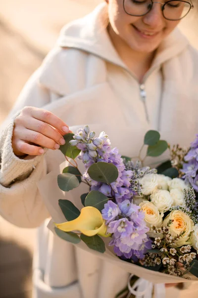 Gadis Tersenyum Muda Mengenakan Mantel Putih Memegang Bunga Mewah Campuran — Stok Foto