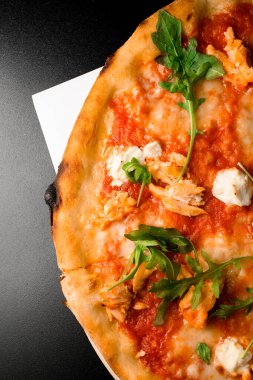 Mozarella peynirli pizza, roka, tavuk parçaları ve ahşap tahtada siyah arka planda sos. Dikey yönelim, Yakın plan görünümü