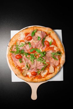 Prosciutto di parma, roka, yarım kiraz domatesli, ananaslı ve parmesanlı lezzetli pizza. İtalyan geleneksel mutfağı. Lezzetli yemek düzlüğü. Üst görünüm