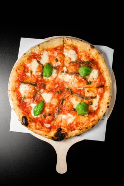 Geleneksel ançüez, kapari, sarımsaklı cips ve taze fesleğen yapraklı mozarella peyniri serpiştirilmiş geleneksel Napoli pizzası. Akdeniz yemeği. İtalyan yenge menüsü