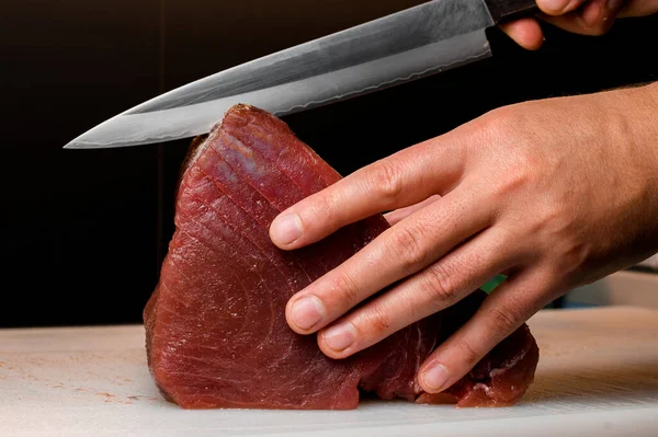 レストラントキッチンで鋭い日本のナイフで細かいマグロの一部をきちんと切断するプロのシェフ サイドビュー ナイリマグロ寿司のための魚肉を準備するシェフ — ストック写真