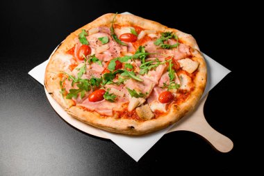 Prosciutto di parma, roka, yarım kiraz domatesleri, tavuk eti, ananas ve ahşap tahtada servis edilen kurutulmuş otlarla lezzetli bir pizza. Geleneksel İtalyan yemeği. Lezzetli yemek.