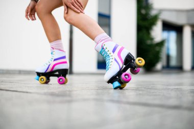 Cropped shot of womans legs in colorful vintage roller skates shoes isolated on white wall background. Female skater. Street outside urban lifestyle clipart