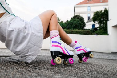 Pembe çoraplı kadın bacakları ve arka planda izole edilmiş renkli eski paten ayakkabıları. Aşırı denge kavramı, sokak şehir dışı yaşam tarzı