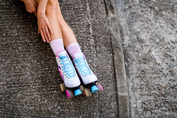 穿着粉色袜子和色彩艳丽的老式轮滑鞋的雌性腿与灰色沥青背景隔离 城市生活方式外的街道 — 图库照片