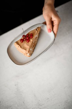 Napolyon 'un klasik Fransız tatlısının bir kısmı kadınların elinde kırmızı frenk üzümü ile süslenmiş, üst manzara. Fırında ya da kafeteryada lezzetli Fransız pastası.