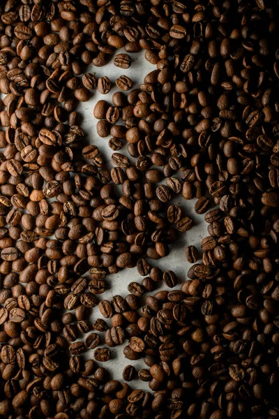 Freshly roasted coffee beans with logo silohuette on white surface, top view. Coffee beans background. Shot can be used as advertisment banner for coffee shop or coffee trade mark