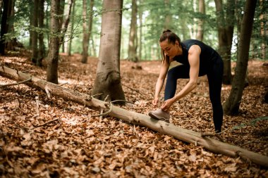 Genç bir kadın ayakkabı bağcıklarını bağlıyor yaz sonu ya da sonbaharda orman yolunda koşuya hazırlanıyor. Aktif sağlıklı yaşam tarzı. Yüksek kalite fotoğraf