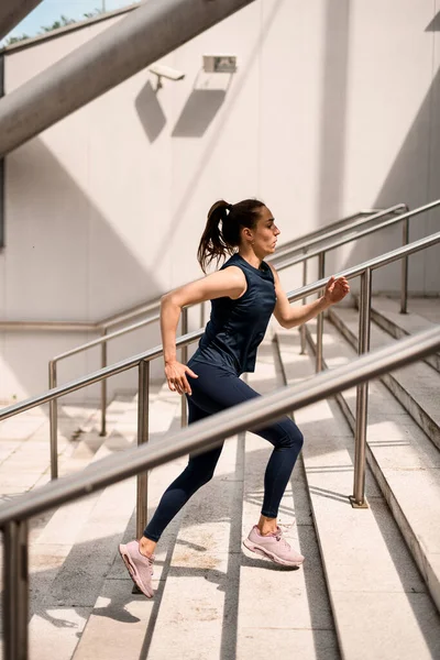 Spor giyimli genç ve çekici bir kadın yaz günü dışarıda antrenmandan önce merdivenlerde ısınıyor. Spor, spor, etkinlik, spor, tatil ve eğitim kavramı.