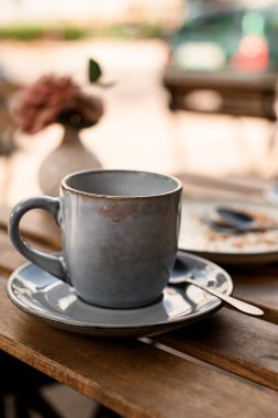 Boş kahve fincanı ve şehirdeki sıcak kahve dükkanının yaz terasında ruj izleri. Mavi arka planda bir demet çiçekli vazo