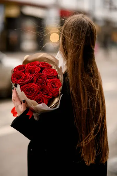 情人节那天 从后面看去 是个长长的黑发女人 手上拿着一大束红玫瑰 穿着深色外套的奢华的时髦女孩 街头照片 — 图库照片