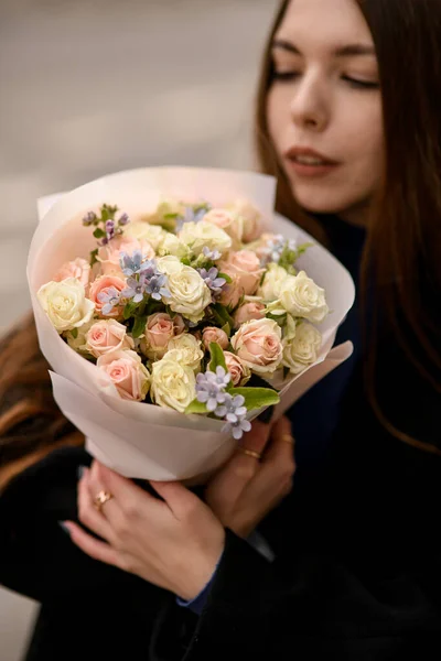 สาวผมยาวท าสนใจถ อดอกไม บอบบางของดอกก หลาบส ชมพ อนและคร มและมองไปบน งขายดอกไม บกล — ภาพถ่ายสต็อก