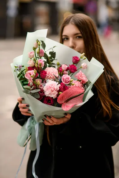 Woman holding delicate flower bouquet of eustoma, carnations, anthurium and eucalyptus wrapped in mint color paper. Beautiful bouquet of fresh mixed flowers. Flower shop