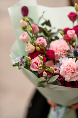 Çiçek buketini östoma, karanfiller, anturyum ve naneli kağıda sarılmış okaliptüs ile kapatın. Güzel bir buket taze karışık çiçek. Çiçekçi. Çiçek teslimatı.