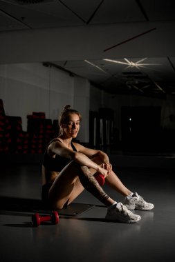 Spor salonundaki antrenmandan sonra ayna karşısında dinlenen sportif bir kadın. Yan görüş. Yan görüş. Sağlıklı yaşam tarzı kavramı.