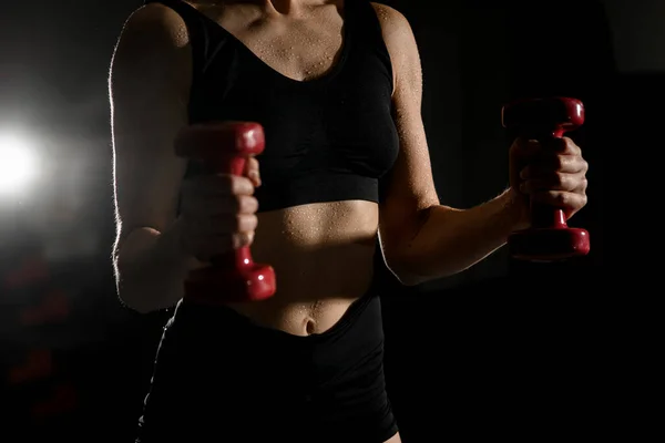 Cropped shot of fitness woman with lifting dumbbells. Well-developed muscles by strength training. Woman ding biceps exercises. Strenght and motivation.
