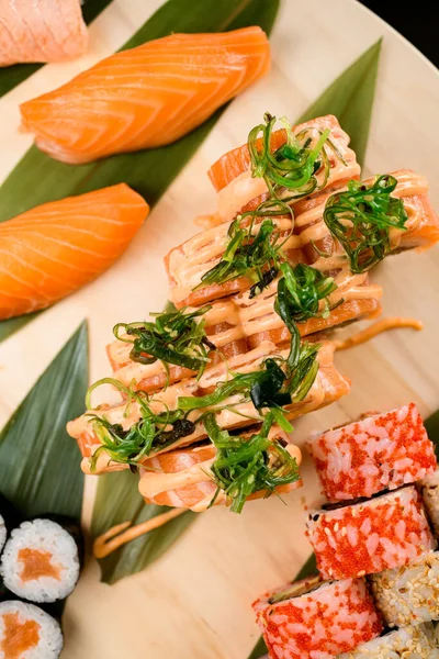 Různé Sushi Rolky Omáčkou Řasami Kulaté Dřevěné Desce Izolované Černém — Stock fotografie