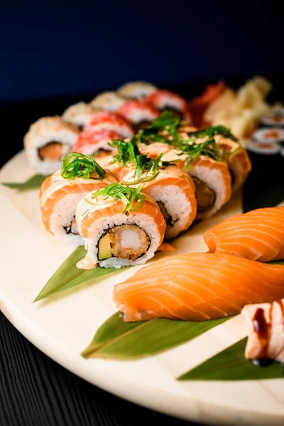 Různé Sushi Role Kulaté Dřevěné Desce Izolované Černém Stole Tmavomodrém — Stock fotografie