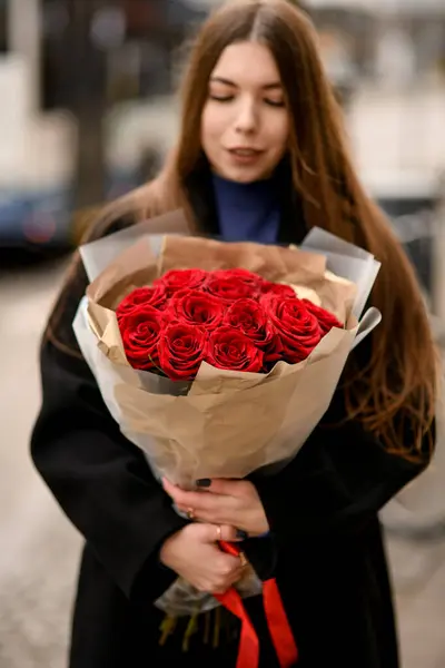 าตาลน กมองไปท อดอกก หลาบส แดงเข มในม อของเธอบนถนน — ภาพถ่ายสต็อก