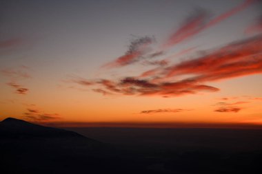 Kış dağlarının güzel manzarası, alacakaranlıkta sis ve parlak bulutlarla çevrili. İnanılmaz bir manzara. Kış mevsimi