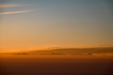 Gün batımında dağ tepelerinde hava manzarası. Kışın yüksek dağ manzarası. Güneş ışığından parlayan muhteşem turuncu akşam manzarası. Dağ zirveleri kar manzarası