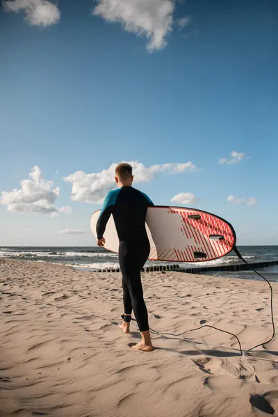Mladý Surfař Kráčí Pláži Neoprénu Drží Prkno Pozadí Modrého Moře — Stock fotografie