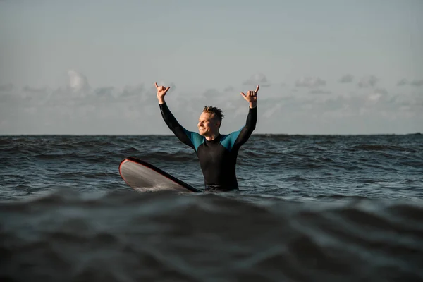 Usmívající Pohledný Mladý Muž Surfař Neoprénu Sedí Moři Surfu Zdviženýma — Stock fotografie