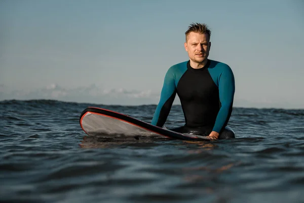 Vážné Pohledný Mladý Muž Surfař Neoprénu Sedí Moři Surfu Zamyšleně — Stock fotografie