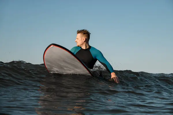 Vážný Pohledný Mladý Muž Surfař Neoprénu Sedí Moři Surfu Dívá — Stock fotografie