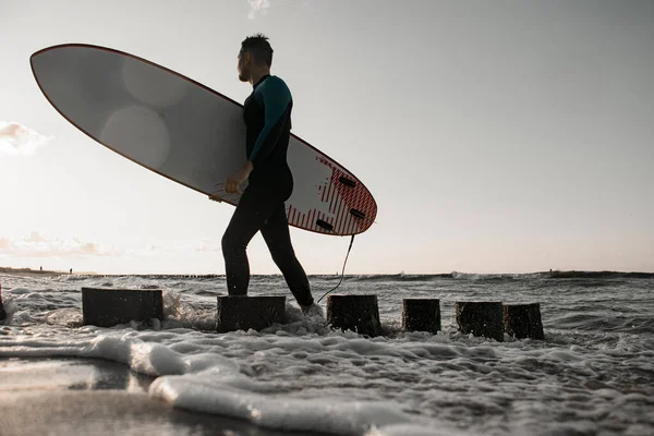 Hezký Mladý Muž Surfař Neoprénu Kráčí Podél Břehu Kolem Dřevěných — Stock fotografie