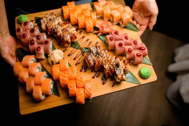 Ton balığı, susam ve teriyaki rulolarından oluşan renkli bir palet. Yapraklı yeşillikler üzerine kurulmuş, bir tutam wasabi de ilave edilmiş..