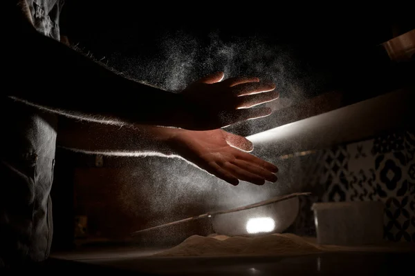 the cooks innovative technique as they rhythmically clap their hands to beat the flour, demonstrating culinary ingenuity.
