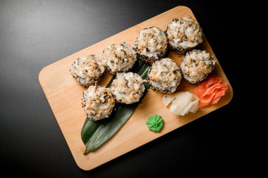 Susamlı pirinçle sarılmış bir rulo. Sıcak wasabi 'li suşi, koyu arkaplanda ahşap bir tahta üzerinde.