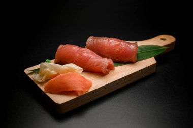 Büyük yeşil yapraklı, wasabi ve zencefil turşulu somon balığı. Siyah zemin üzerinde kırmızı balık olan ahşap tahta tahta.