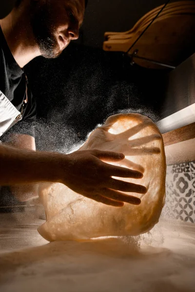 Observe the skilled chef as they expertly demonstrate the art of tossing pizza dough, showcasing their culinary expertise.