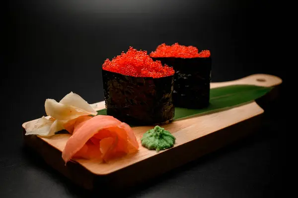 Sushi Par Tjock Träskiva Med Röd Kaviar Svart Bakgrund Insvept — Stockfoto