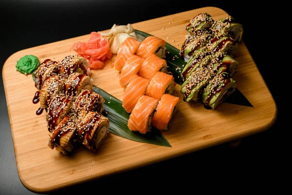 Texturované Dřevěné Desky Černém Pozadí Různými Sushi Sady Dlouhých Zelených — Stock fotografie