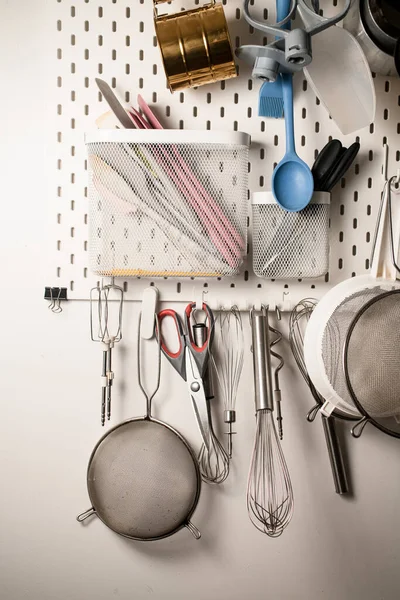 Kitchen wall organizer that holds sieves, silicone spatulas, spoons and other various confectioners accessories, isolated