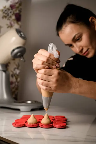Confeiteiro Feminino Espreme Creme Bege Saco Pastelaria Metades Vermelhas Macaroons — Fotografia de Stock