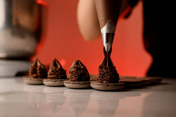 Tangan Wanita Memeras Krim Coklat Bagian Bundar Dari Makaroni Coklat — Stok Foto