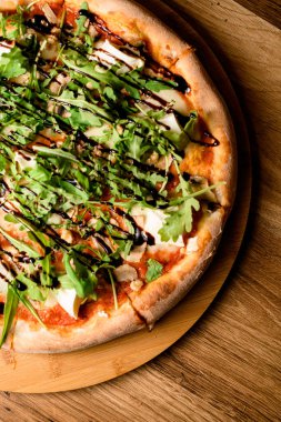 Ahşap bir tezgahta ahşap bir masa üzerinde deniz mahsulü roka ve mozzarella ile pizza.